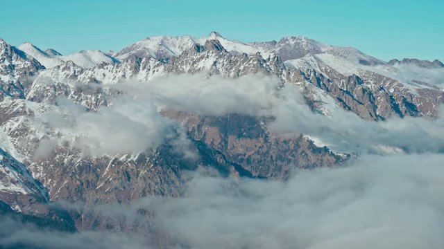 Snow capped mountains above clouds in a blue sky in sunny weather