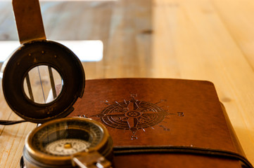 vintage book, with a wind rose engraved on the cover, and next to it, an antique bronze compass