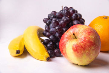 Naklejka na ściany i meble Still life of fruits on a white background, banana, apple, grapes