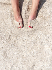 Top view of female legs with red pedicure in the beach sand. Rest and recreation at sea. Copy space. High quality photo. Flat lay.