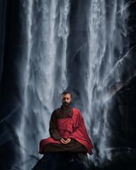 A Buddhist meditates in the cross-legged lotus position. In the background, a waterfall in the wild. The concept of a healthy lifestyle and mental balance.