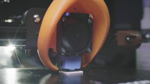 The 3D printer prints an abstract cube shape from white abs plastic. 3D printer head in action. An automatic three-dimensional 3d printer performs plastic. Macro