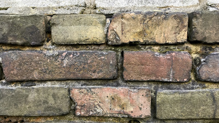 Fragment of old brick wall of red brickwork which darkened from time. Abstract retro wall background. Use as art background. 16x9 format. Close-up. Selective focus.