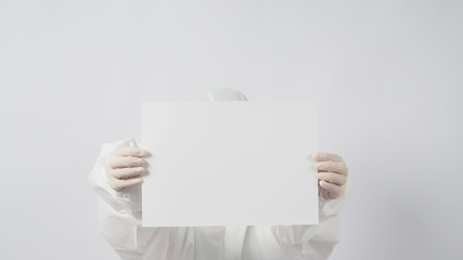 Female model wearing PPE and face mask and Hand with gloves is holding A4 paper on white background.