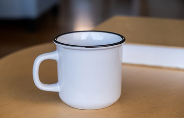 Coffee mug mockup on a wooden table, blurred background.