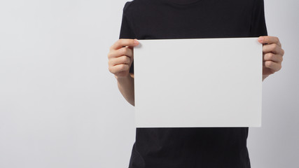 Female hand is holding the A4 paper and wear black t shirt on white background.