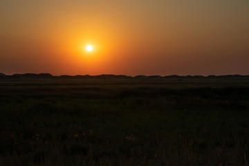 Sunset over the grassland between the dike and the beach on the North Sea coast.