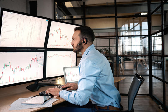 Stock Traiding. Trader sitting at office wearing headset doing online trading training monitoring candlestick price chart concentrated