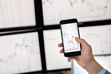 Trader holding smartphone with mock up of index on cryptocurrency diagram