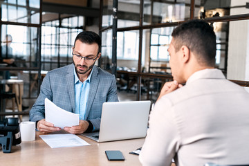 Recruitment Concept. Manager looking at resume of candidate impressed sitting at office