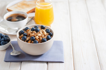 Coffe with granola and blueberry and baked toasts tasty breakfast on the white wooden table with copy space