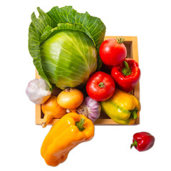 A set of vegetables: cabbage forks, tomatoes, bell peppers, onions and garlic in a wooden box isolated on a white background. Harvest concept. Healthy eating. Top view