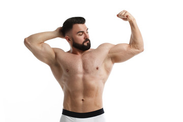 Fototapeta na wymiar Athletic bearded man with a naked muscular torso holds one hand behind his head, the other demonstrates muscles, isolated on a white background.