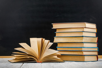 A stack of books on a white table against a blackboard.