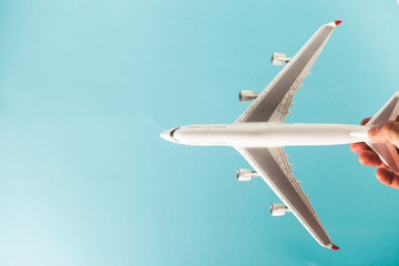 Obraz premium man's hand holding white airplane model over the turquoise background