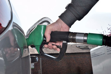 Hand hold Fuel nozzle to add fuel in car.