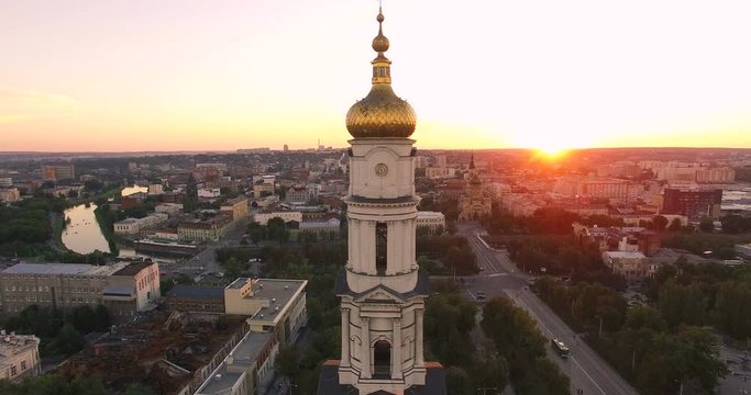 Aerial view to Holy Dormition Cathedral (Uspenskiy sobor) at sunset with panorama of Kharkiv city, Ukraine. Camera lifting