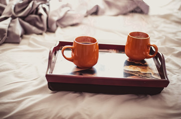 two cups of hot drink on a tray in bed, morning breakfast