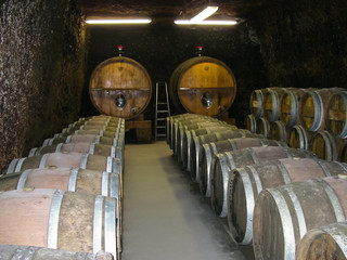 Wine cellar with barrels of wine from a French winemaker. Aging of wine in oak barrels.
