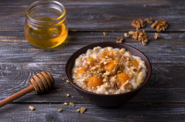 Delicious oatmeal porridge with baked pumpkin, honey and nuts in ceramic bowl on wooden table. healthy homemade breakfast. selective focus