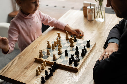 dad and little daughter play chess in an intelligent cafe