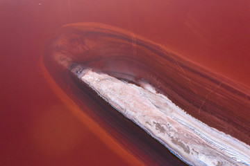 Pink salt lake with an island in the center, top view.