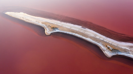 Pink salt lake with an island in the center, top view.