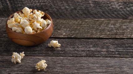 Salty popcorn in a wooden bowl in rustic style. Copy space