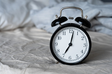 Stylish alarm clock with a bell. The hands show 7 hours. Wake up time