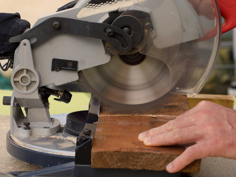Close up of a carpenter using a circular saw to cut a plank of wood