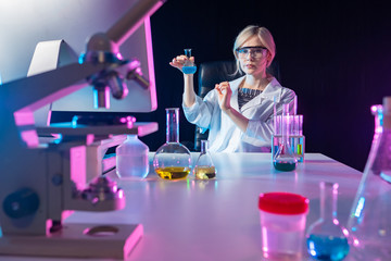 The girl works in a chemical laboratory. A woman with a flask in her hands. Chemist on the...