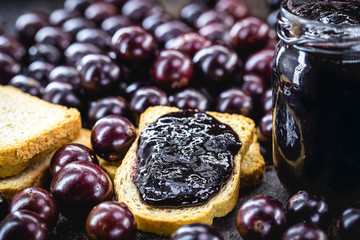 toast with grape jam, on rustic wooden table. Jabuticaba, exotic Brazilian fruit, used in cooking, as a sweet.