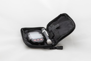 Fototapeta premium Set for measuring blood sugar. Measuring instrument and pen in a black case. Photo on a white background.