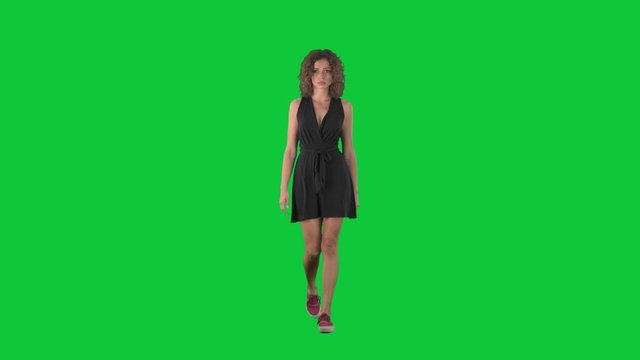 Serious displeased young woman walking and looking at camera on green screen chroma key background. 