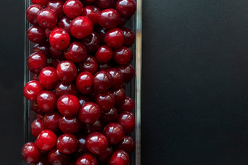 Cherry berries in glass platter isolated on black background. Delicious berries. Harvesting concept.