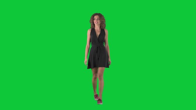 Amazed young shopping woman walking and looking at prices discount on green screen chroma key background. 