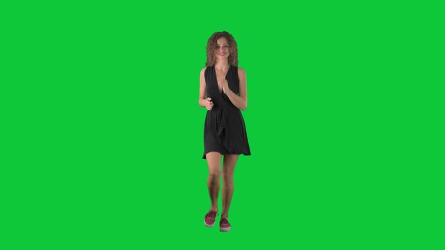 Cheerful young beautiful woman jogging in dress smiling at camera on green screen chroma key background. 