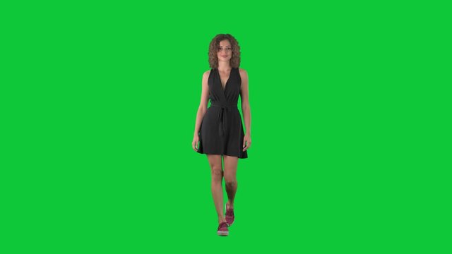 Happy casual style woman in mini dress walking and smiling at camera on green screen chroma key background. 