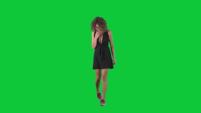 Young concerned stylish woman walking looking down searching for something lost on green screen chroma key background. 