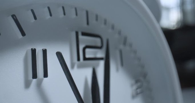 High Noon Alarm Clock. Extreme macro wide angle close up as the second hand ticks past the 12 on a small alarm clock with raised 3D numbers.