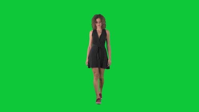Young sad worried woman walking and looking down on green screen chroma key background.