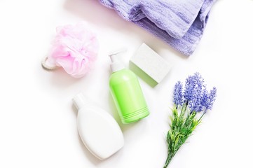 White shampoo bottle, green liquid soap package, purple cotton towel, pink sponge and lavender bouquet. Flat lay photography organic natural herbal cosmetics for skin and hair care