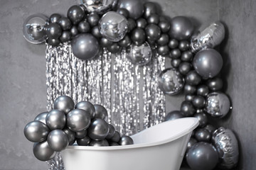 black and white photo white stylish bathtub in empty room with balloons and confetti