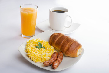Desayuno con huevos revueltos con salchicha, pan, café y jugo