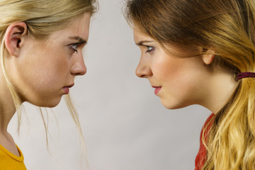 Two girls looking serious at each other.