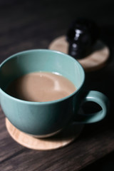 Cup of coffee on dark wood table and ornament in the background