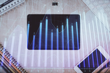 Double exposure of forex graph hologram over desktop with phone. Top view. Mobile trade platform concept.