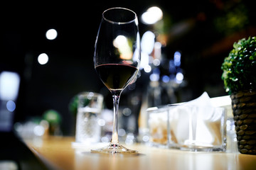 a glass of red wine on a table in a bar