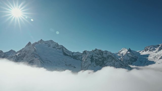 Snow capped mountains above clouds in a blue sky in sunny weather