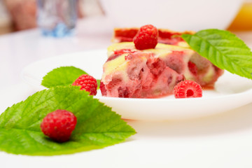 raspberry piroke on a white table, garnished with raspberries and raspberry leaves.